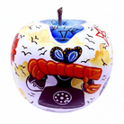 A hand-painted ceramic decorative apple with a white base, featuring a whimsical illustration of a red telephone, blue butterflies, black birds, and yellow clouds, complete with a brown stem.