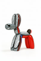 Metallic balloon dog sculpture with red, silver, and black colors on a white background