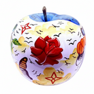 A decorative ceramic apple-shaped candle holder with a hand-painted design featuring a large red rose, yellow clouds, black birds, and a green apple stem.